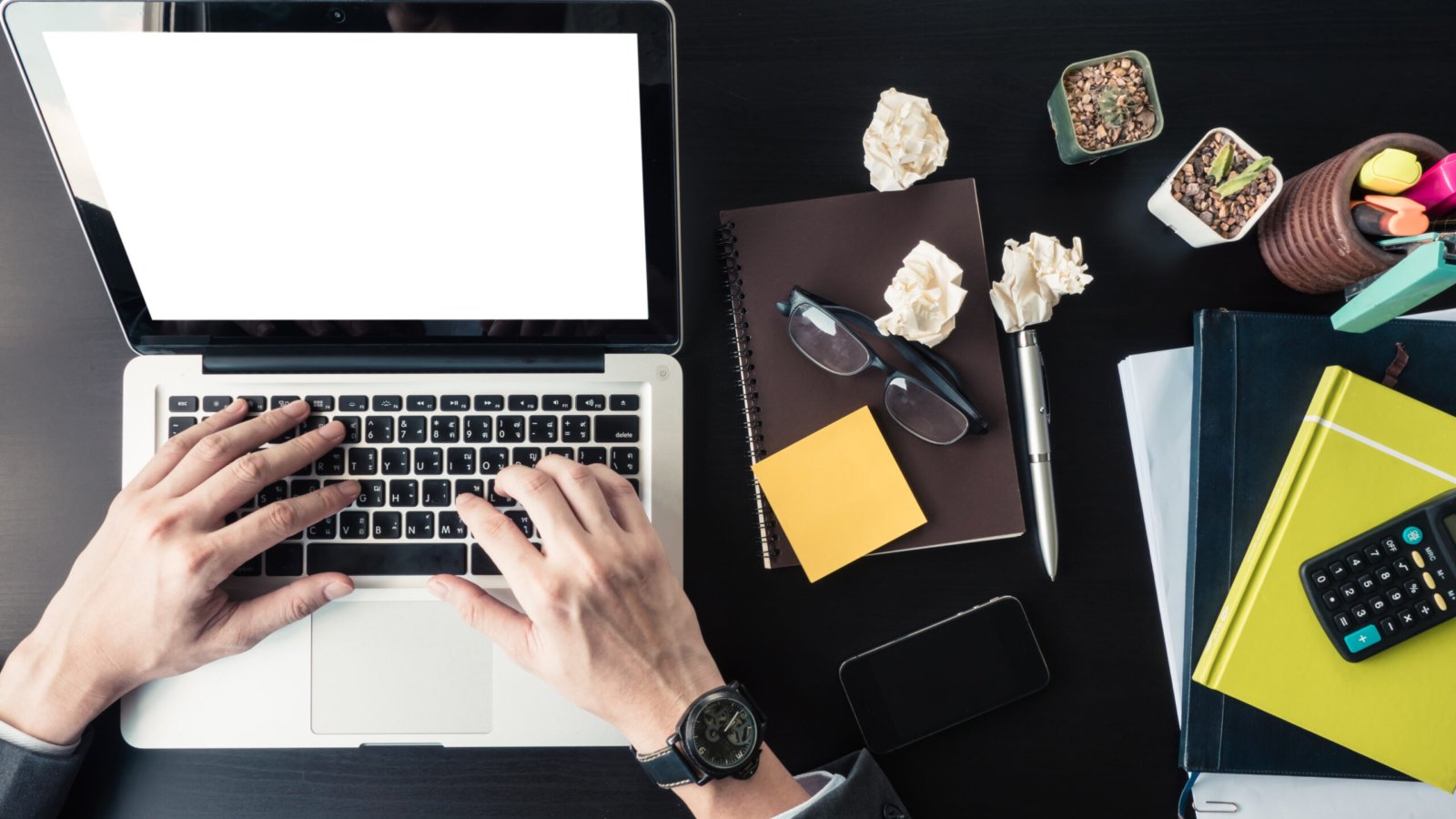 Top view of Businessman using Laptop with office supplies on the office desk.