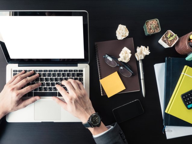 Top view of Businessman using Laptop with office supplies on the office desk.